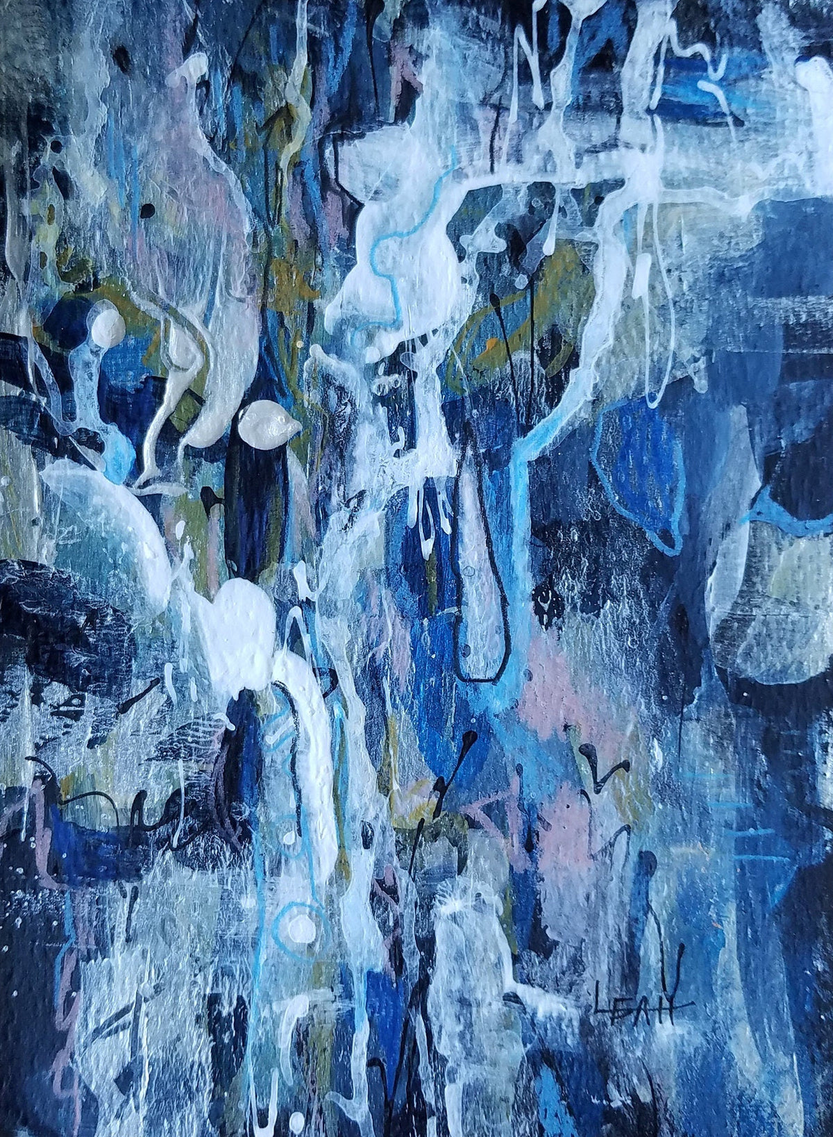 An abstract blue and white painted artwork with layered brushstrokes and splashes of gray, black, and faint pink, displayed on a brown wooden surface.