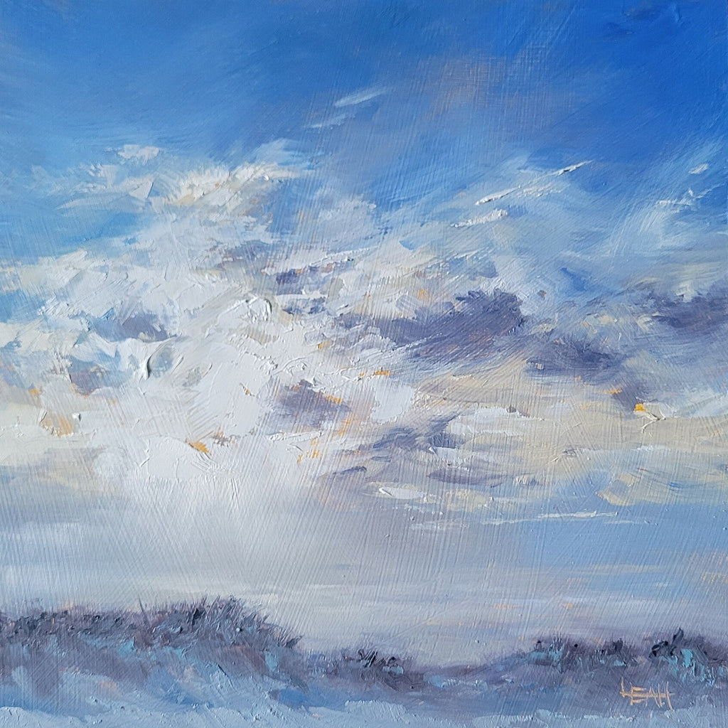 A square canvas painting of a cloudy blue sky over a low landscape, displayed on a wooden surface.